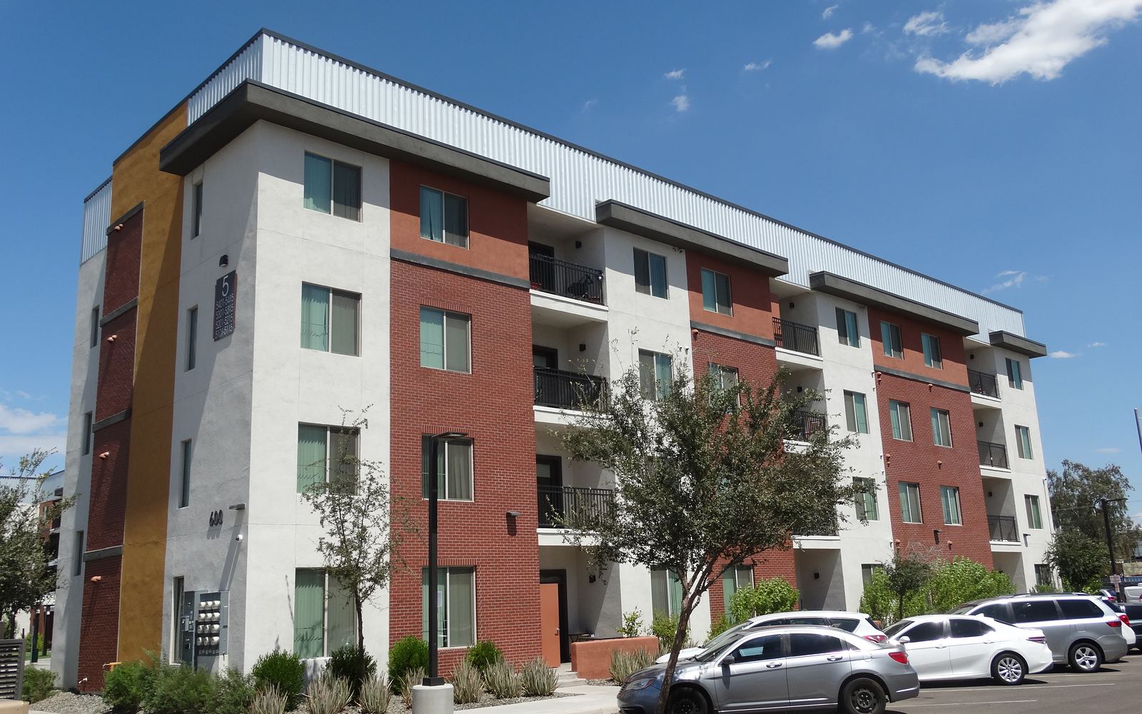 Harmony, a four-story apartment building with a finished white, red brick, and gold exterior