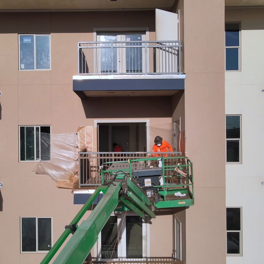 Painter on a boom lift at an upper-floor balcony