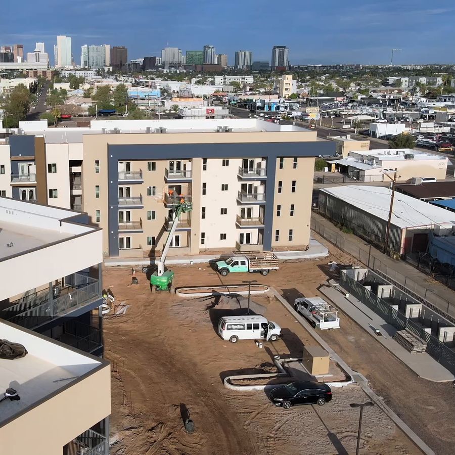 Aerial view of an apartment building with a boom lift and crew trucks, downtown Phoenix behind